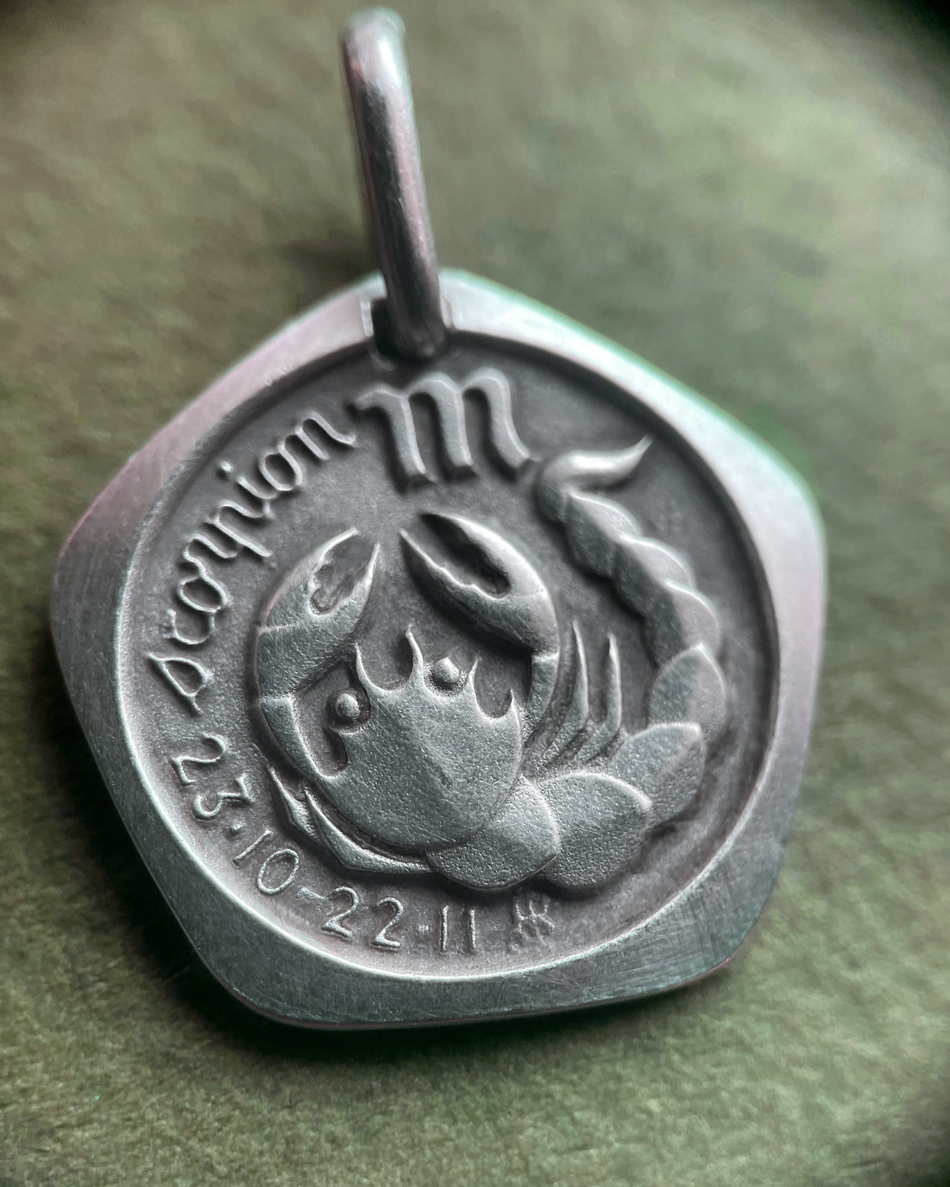 Close-up of 1970s French 800 silver Scorpio zodiac pendant through jeweller’s loupe showing detail – Auric Vintage