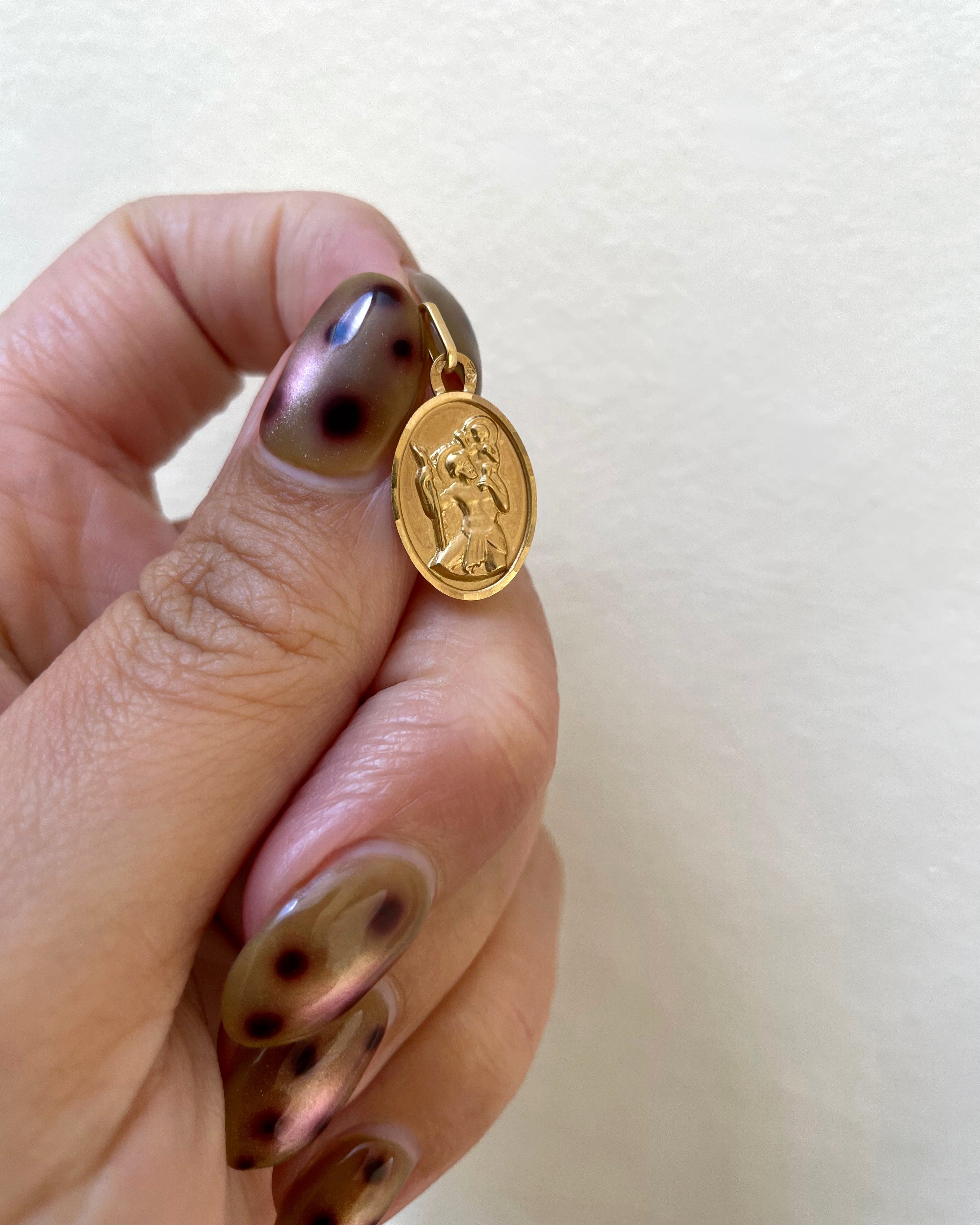 1950s French mini oval St. Christopher pendant in 18kt yellow gold held in hand showing scale and haloed figural relief – Auric Vintage
