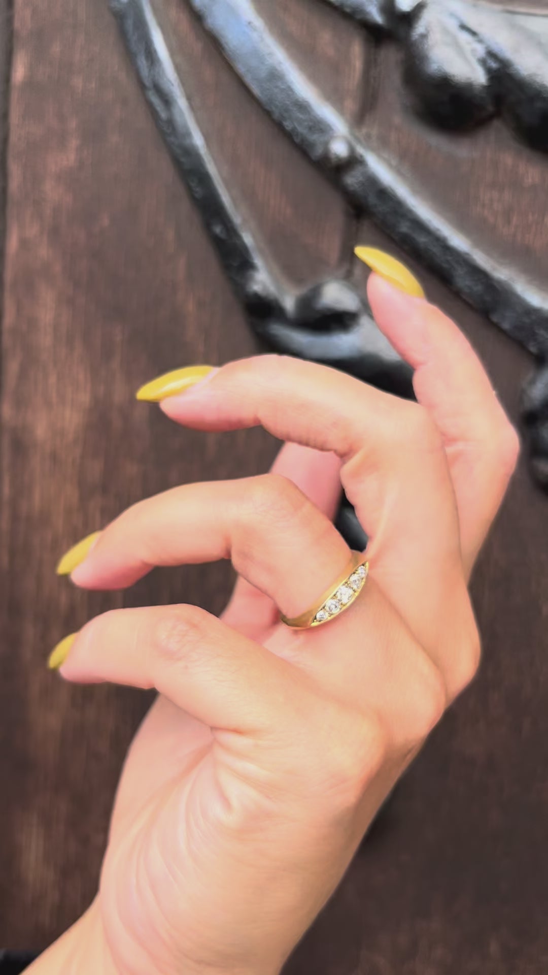 Antique Victorian 18kt gold navette ring with five diamonds totalling approximately 0.50ct, shown worn on a hand against a dark wood door.