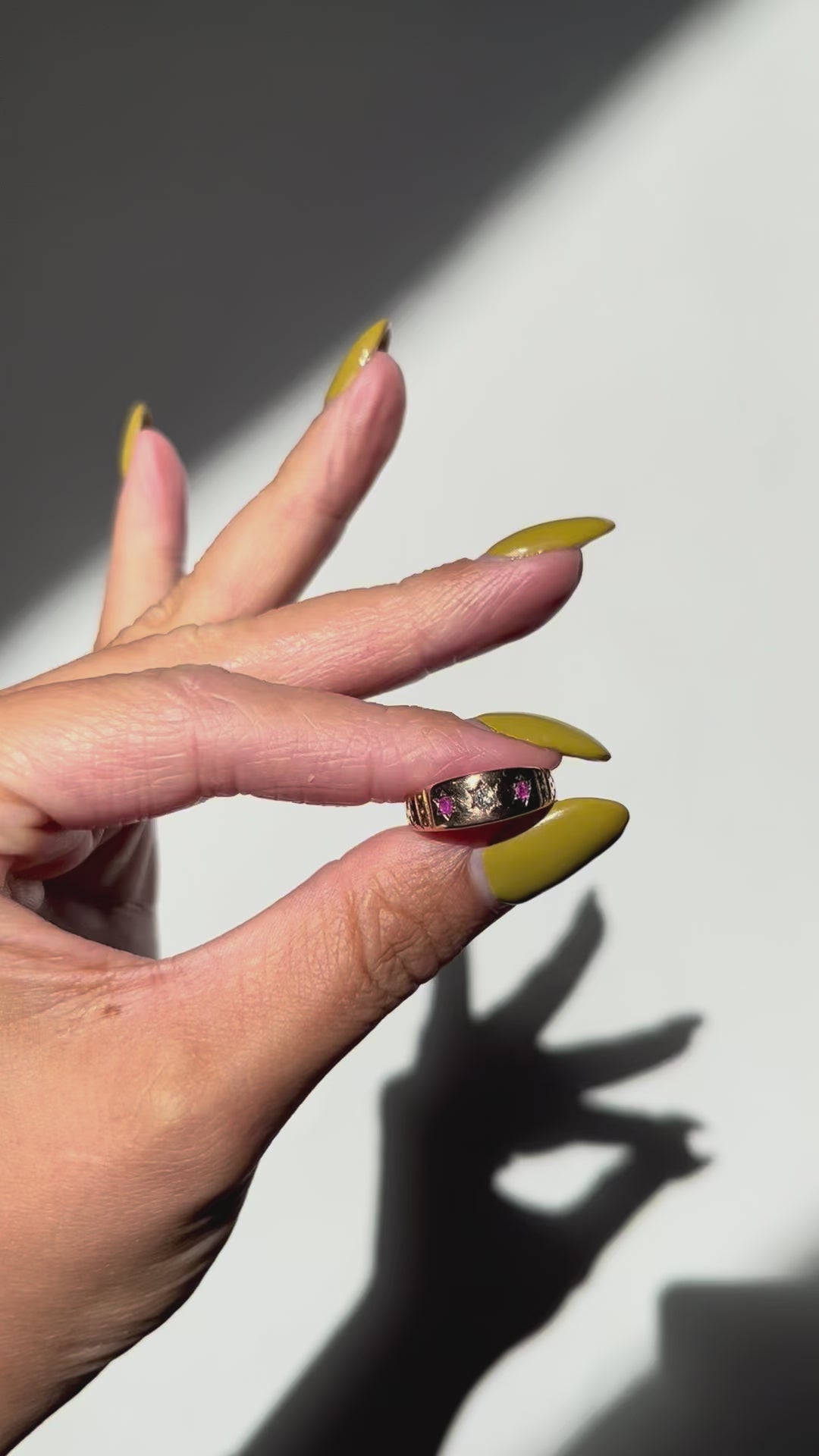 Video of an antique 15kt gold gypsy set diamond and ruby ring shown worn on a hand against a white wall, highlighting the flush-set star motifs and engraved shoulders.