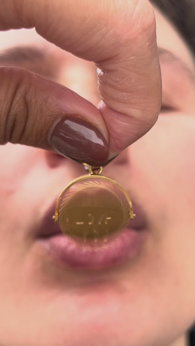 Vintage 1970s 9kt gold “I Love You” pendant being gently blown and spun to reveal its hidden “I LOVE YOU” message.