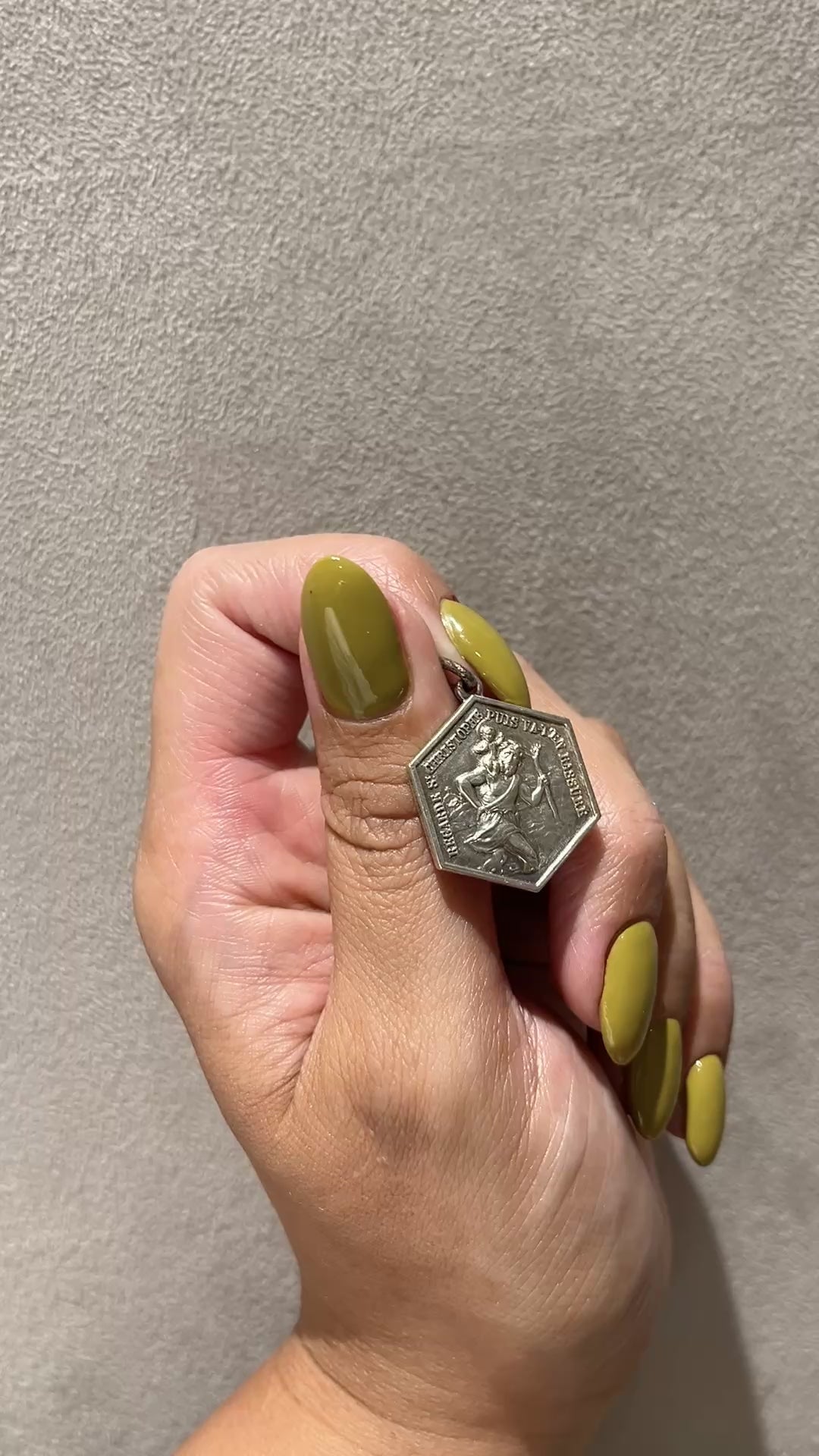 French vintage St. Christopher Lourdes pendant featuring St. Christopher carrying the Christ Child on the obverse and the Apparition of the Virgin Mary to Saint Bernadette on the reverse, shown held in a hand