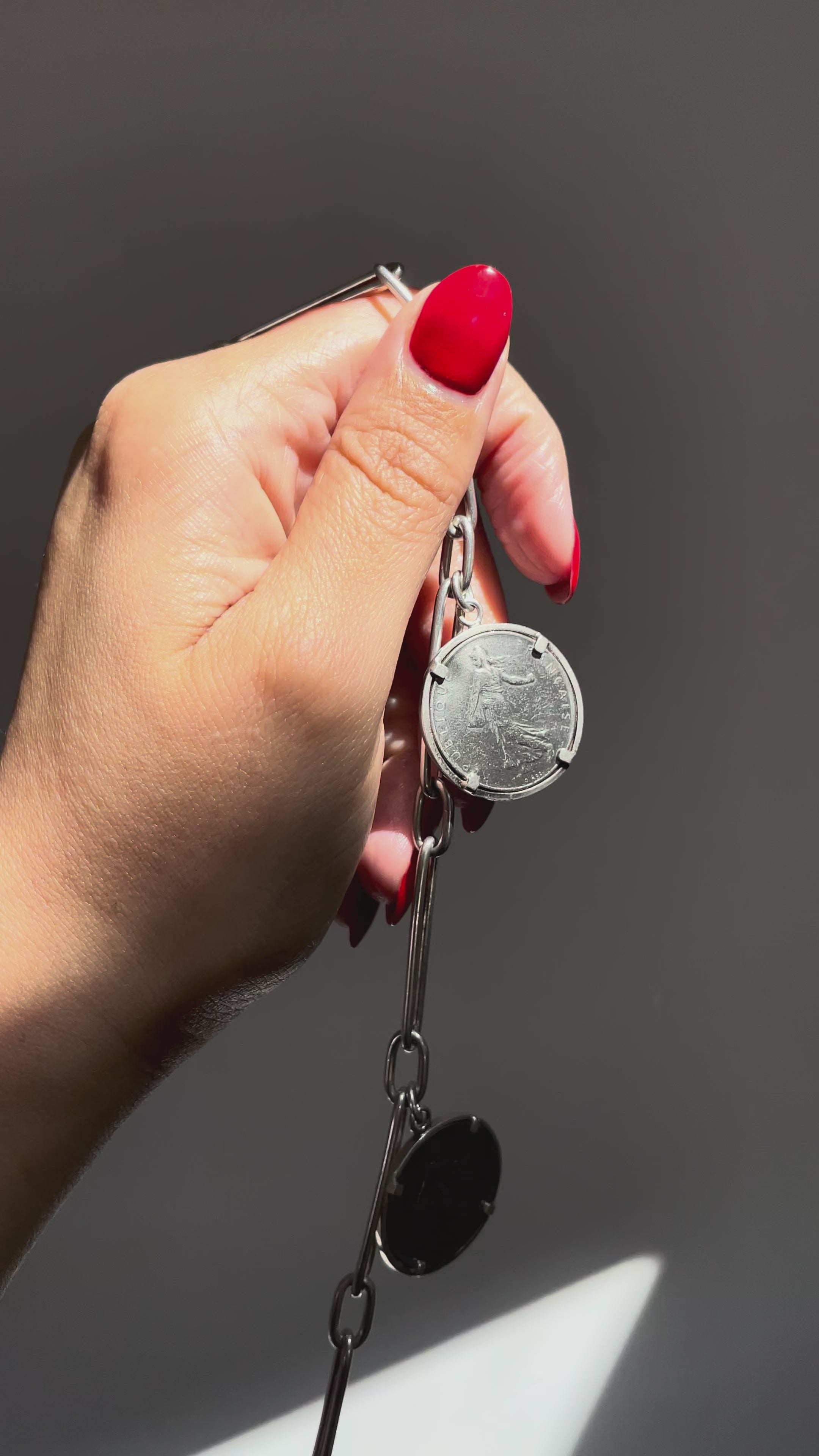 Video of Arthus Bertrand 1 Franc coin sautoir in sterling silver held in hand showing movement and coin detail – Auric Vintage